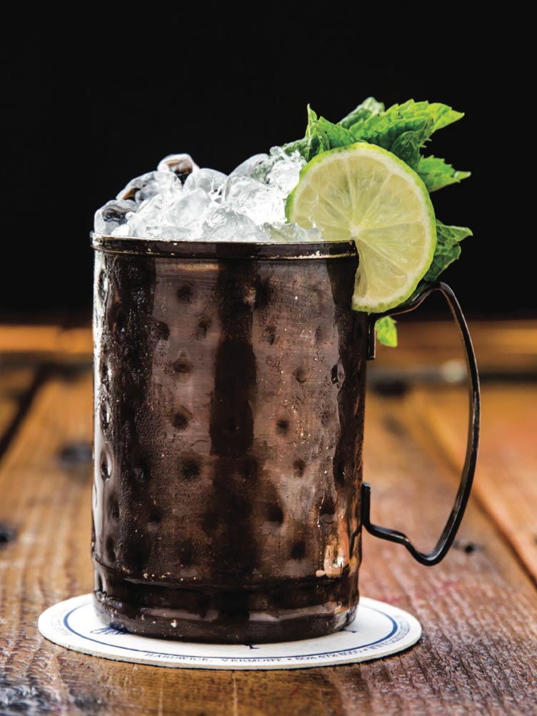 Cocktail in a copper mug with ice and a lime wedge