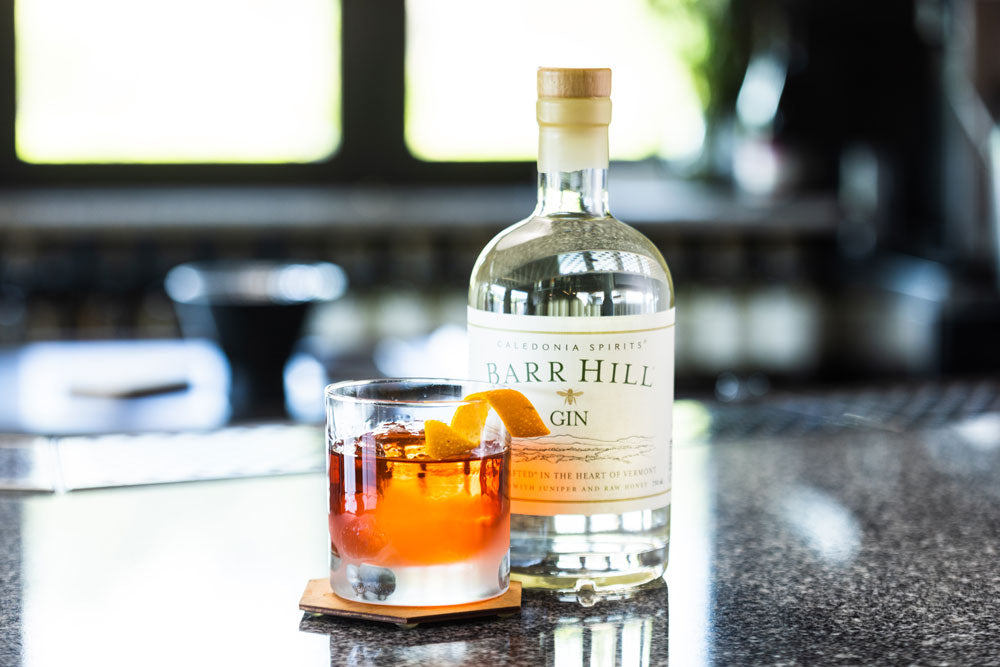 A Gin Negroni in a cocktail glass next to a bottle of Barr Hill Gin