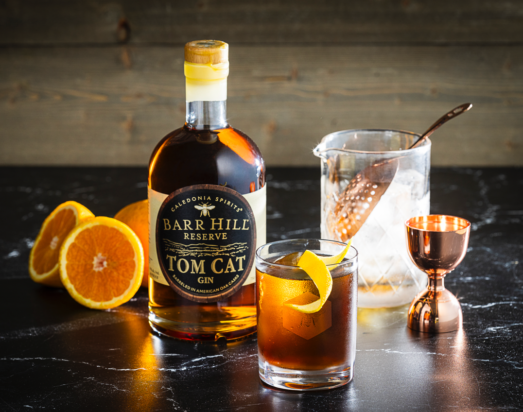 Dark, winter style Negroni cocktail with a bottle of barrel aged gin, mixing glass and orange slices